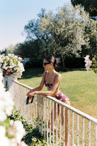 Aura - Bikini in Plum / Pink Polka Dot — side profile at the garden railing